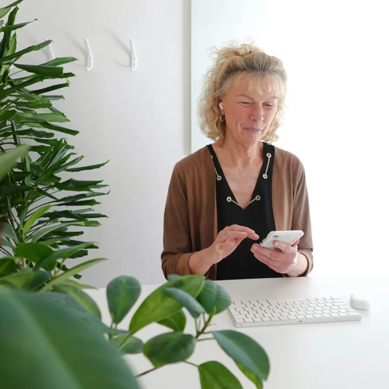 Susanne sitter med mobiltelefon i handen och ett tangentbord framför sig